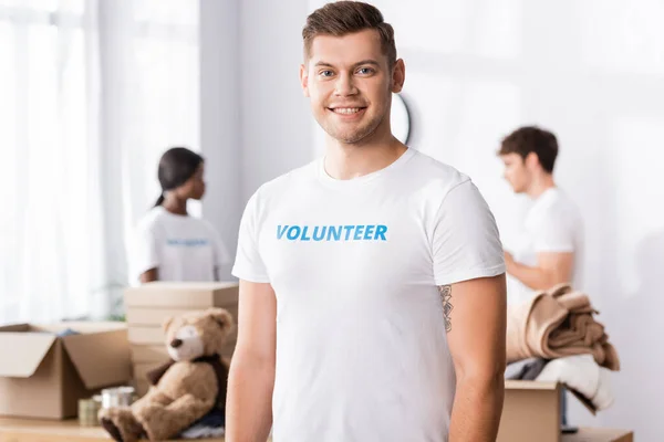 Selective focus of young volunteer looking at camera in charity center — Stock Photo