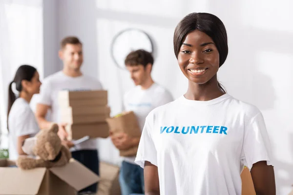 Selective focus of african american volunteer looking at camera in charity center — Stock Photo