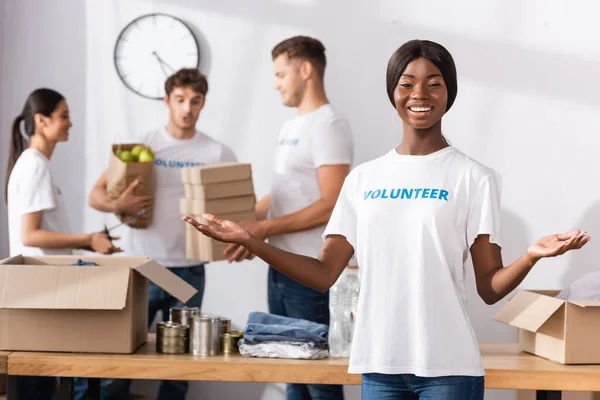 Selective focus of african american volunteer pointing with hands near donations in charity center — Stock Photo