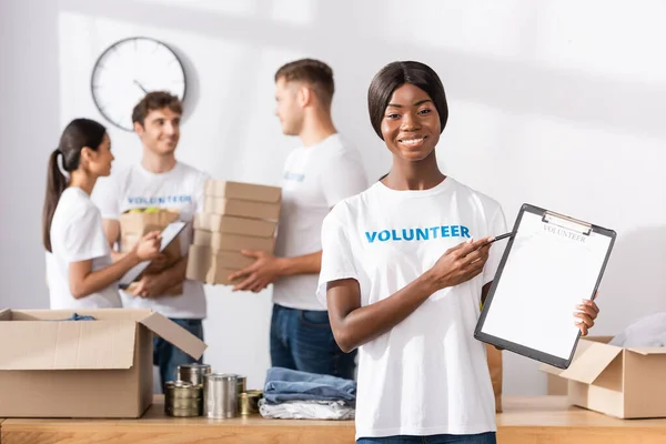 Foco seletivo do voluntário afro-americano apontando para a área de transferência no centro de caridade — Fotografia de Stock