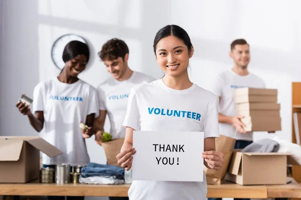 Selective focus of asian woman holding card with thank you lettering in charity center — Stock Photo