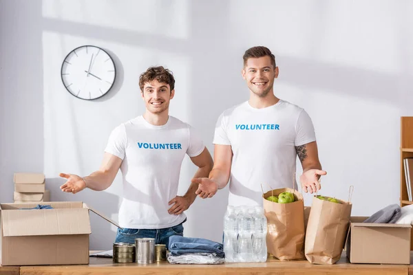 Voluntarios señalando con las manos a las donaciones en el centro de caridad - foto de stock