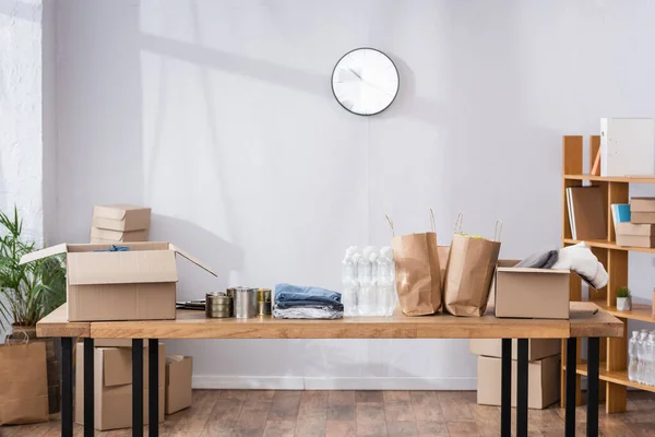 Paper bags, tin cans and carton boxes on table in charity center — Stock Photo