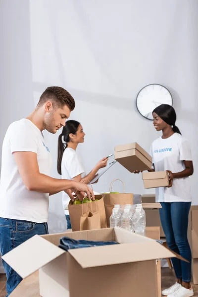 Focus selettivo del volontario mettere le mele in sacchetti di carta in un centro di beneficenza — Foto stock