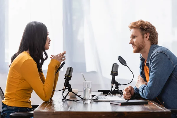 Vista laterale della giovane donna asiatica che parla con l'emittente rossa durante l'intervista in studio — Foto stock