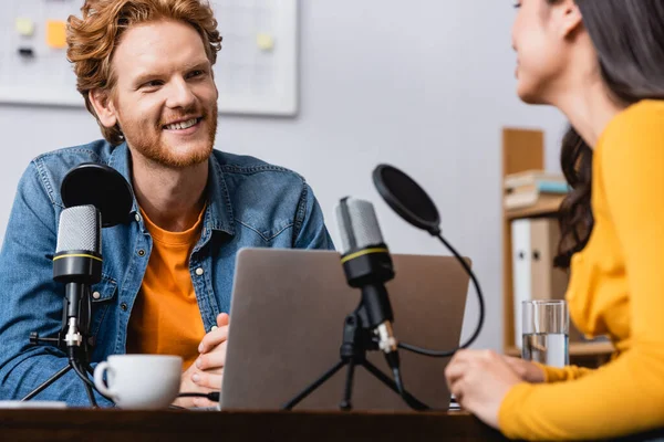 Selective focus of excited redhead radio host interviewing young woman in studio — Stock Photo