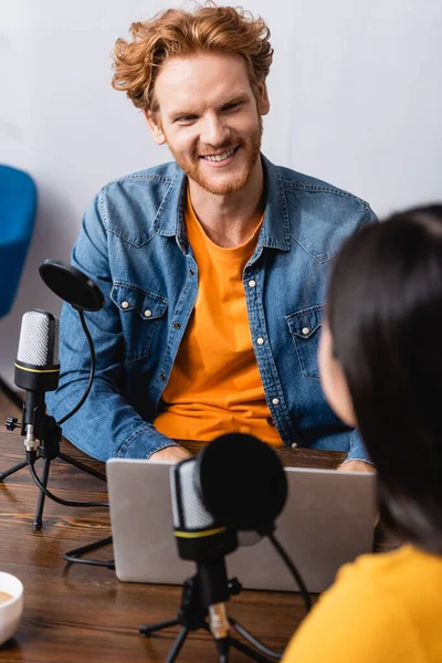 Selective focus of excited redhead radio host interviewing brunette woman in studio — Stock Photo