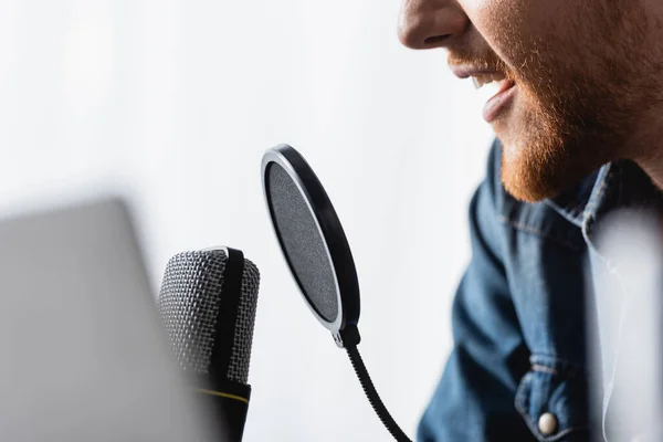 Visão cortada de emissora barbuda falando em microfone, foco seletivo — Fotografia de Stock