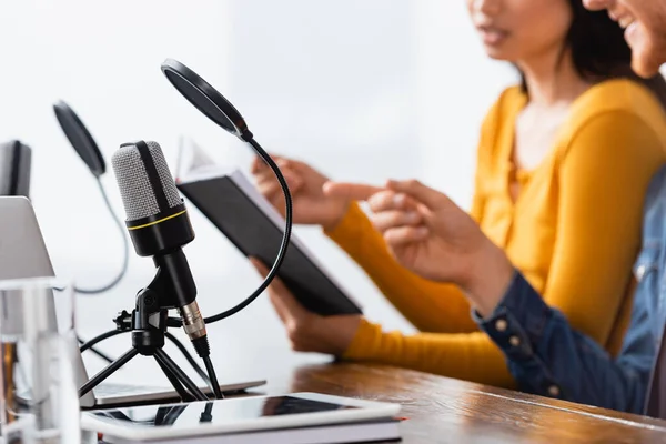 Vista cortada de locutor apontando para notebook em mãos de colega perto de microfones e tablet digital — Fotografia de Stock