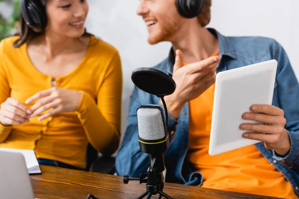 Selective focus of broadcaster pointing at digital tablet near colleague at workplace — Stock Photo