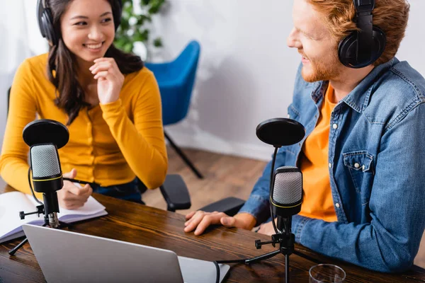 Enfoque selectivo de asiático radio host hablando con colega en estudio de radio - foto de stock