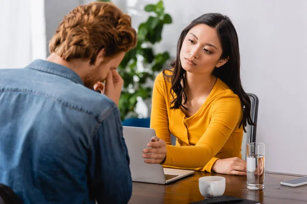 Jeune diffuseur asiatique étirant la main près confus homme toucher le visage pendant l'interview — Photo de stock