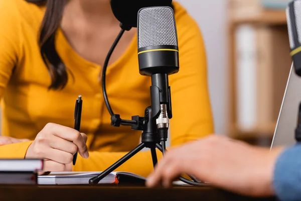 Cropped view of broadcaster holding pen during interview with man in radio studio — Stock Photo