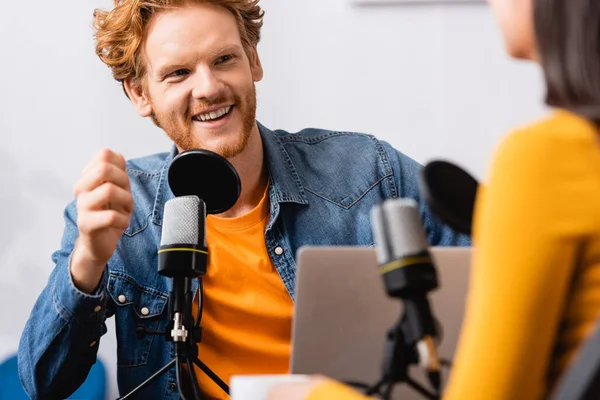 Enfoque selectivo de anfitrión de radio emocionado entrevistando a mujer en estudio de radio - foto de stock