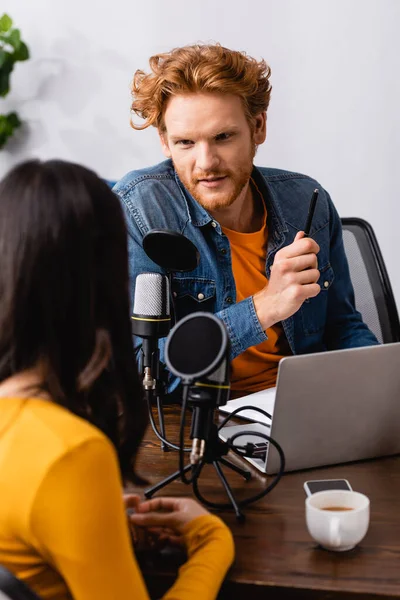 Vista posteriore di donna bruna vicino a giovane intervistatore rossa in studio radio — Foto stock