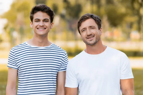 Pai e filho adolescente em camisetas olhando para a câmera fora — Fotografia de Stock