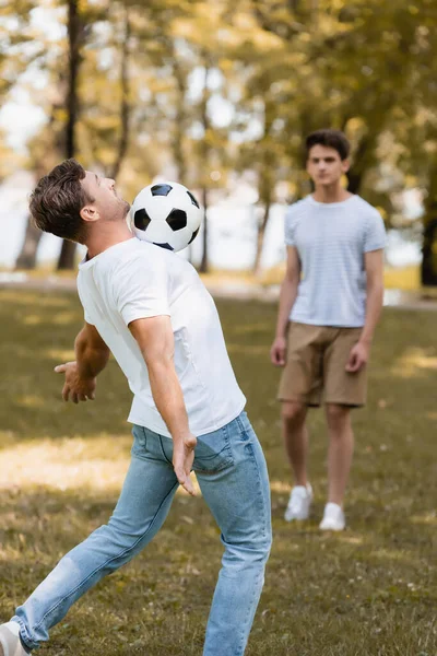 Selective focus of father playing football with teenager son — Stock Photo