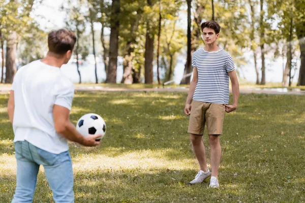Enfoque selectivo de hijo adolescente mirando al padre con el fútbol - foto de stock