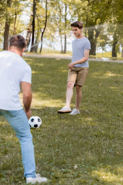 Enfoque selectivo de hijo adolescente jugando al fútbol con el padre - foto de stock