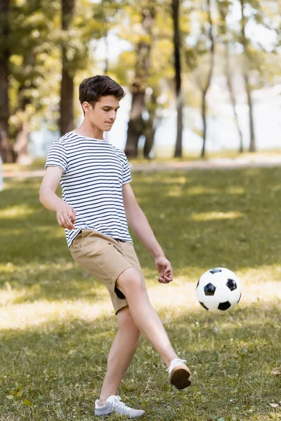 Teenager boy in stripped t-shirt playing football outside — Stock Photo