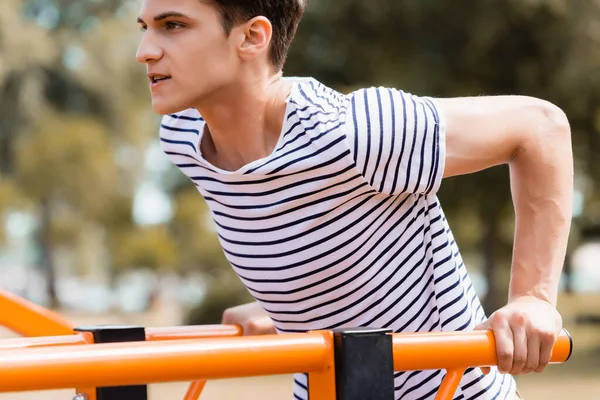 Strong teenager boy exercising on horizontal bars — Stock Photo