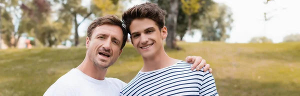 Image horizontale du père excité et du fils adolescent dans le parc — Photo de stock
