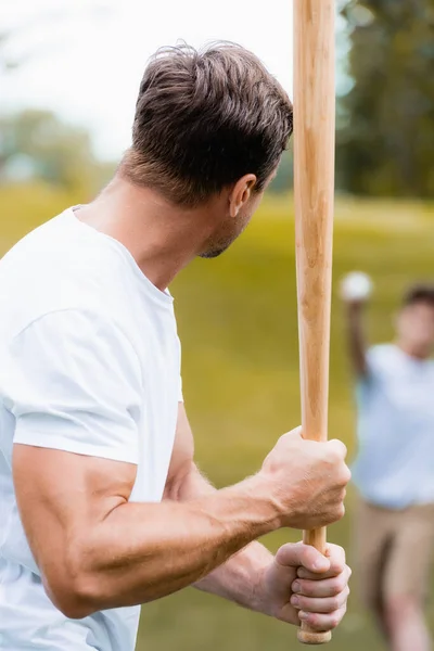 Enfoque selectivo de padre sosteniendo bate de softbol cerca de adolescente - foto de stock