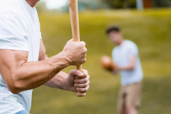 Recortado vista de hombre sosteniendo softball bat cerca adolescente chico - foto de stock