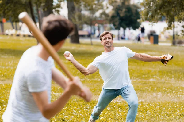 Foco seletivo do pai na luva de couro segurando bola e jogando beisebol com o filho no parque — Fotografia de Stock
