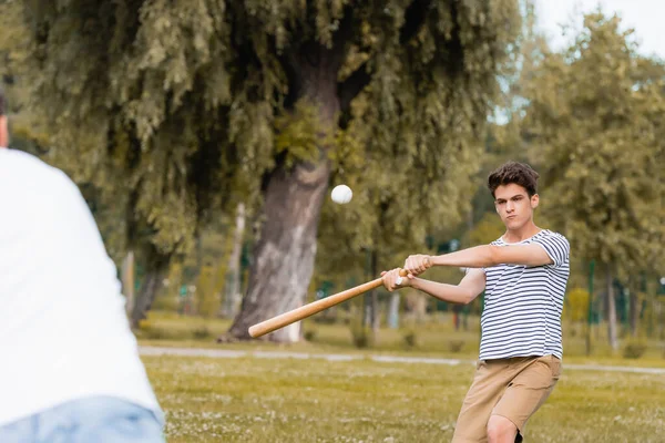 Foco seletivo do menino adolescente com bastão de softball jogando beisebol com o pai no parque — Fotografia de Stock