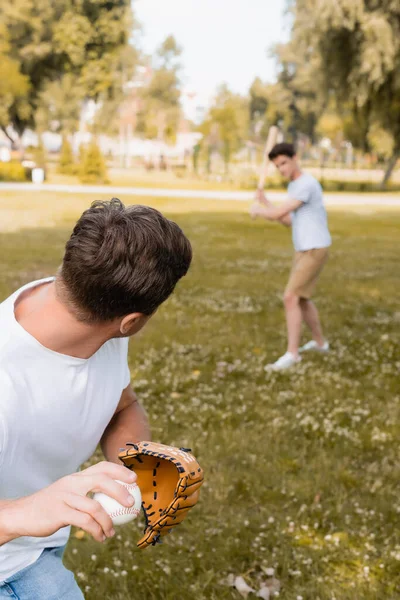 Messa a fuoco selettiva del padre in guanto di pelle che tiene la palla mentre gioca a baseball con il figlio adolescente nel parco — Foto stock