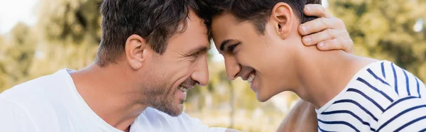 Horizontal crop of joyful father and teenager son looking at each other — Stock Photo