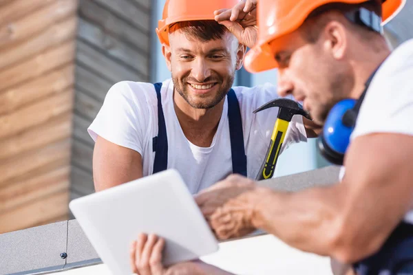 Selective focus of handymen using digital tablet on roof of building — Stock Photo