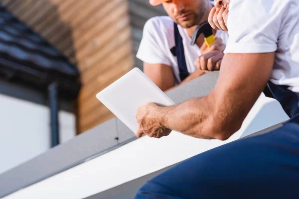 Cropped view of builders using digital tablet on roof of house — Stock Photo
