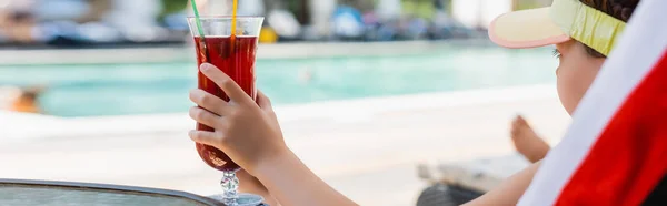 Горизонтальное изображение девушки в козырьке для загара, держащей коктейльный бокал во время отдыха в шезлонге — стоковое фото