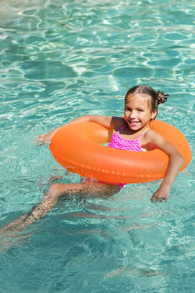 Дитина дивиться на камеру під час плавання на кільці в басейні — стокове фото