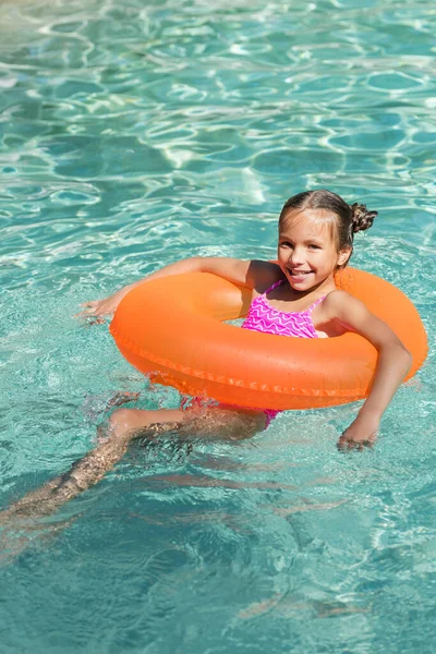 Niño mirando a la cámara mientras flota en el anillo de natación en la piscina - foto de stock