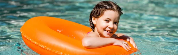 Panoramisches Konzept des Mädchens, das auf dem Schwimmring in die Kamera blickt — Stockfoto