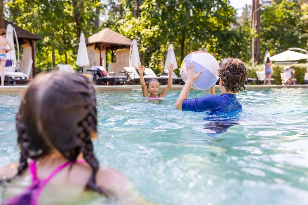 Foyer sélectif des amis jouant dans la piscine avec la boule gonflable — Photo de stock