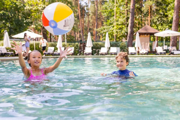 Enfoque selectivo de amigos emocionados jugando con la bola inflable en la piscina - foto de stock