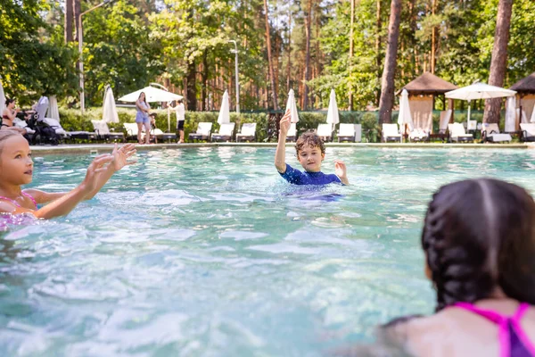 Вибірковий фокус хлопчика і двох дівчат, які розважаються в басейні — стокове фото