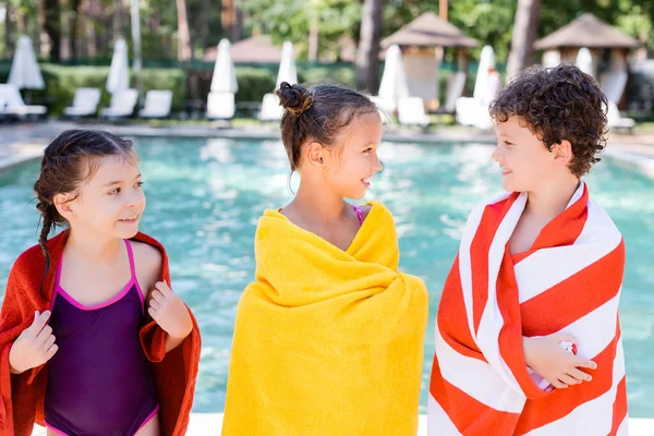 Girl in swimsuit near friends looking at each other while wrapping in terry towels — Stock Photo