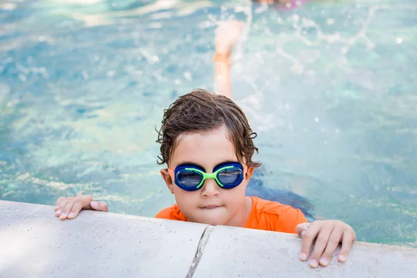 Мальчик в очках для плавания в воде возле бассейна — стоковое фото