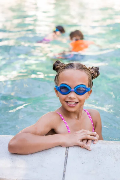 Kind mit Schwimmbrille blickt am Pool in Kamera — Stockfoto