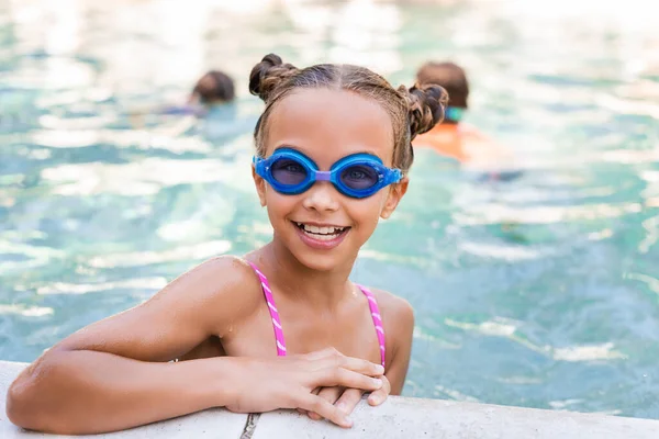 Девушка в очках для плавания смотрит в камеру у бассейна — стоковое фото