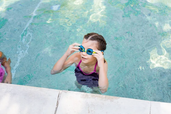 Vue grand angle de fille dans la piscine toucher lunettes de natation tout en regardant loin — Photo de stock