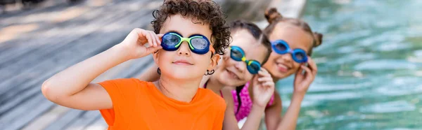 Сайт заголовок мальчика и девочки касаясь очки плавания при взгляде на камеру, панорамная ориентация — стоковое фото
