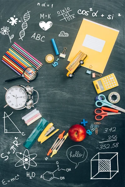 Top view of frame with vintage alarm clock, green apple and school supplies on black chalkboard with illustration — Stock Photo