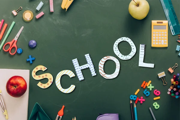 Vista superior do quadro com maçãs maduras e material escolar em quadro-negro verde com letras escolares — Fotografia de Stock