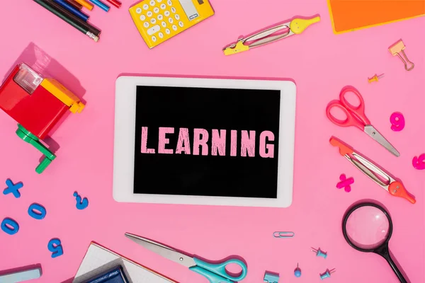 Вид зверху цифрового планшета з навчанням написання на екрані біля шкільних канцелярських приладів на рожевому — стокове фото